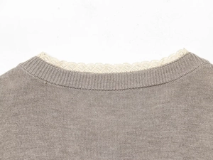 Close-up of crew neckline with delicate white lace trim on taupe knitted sweater