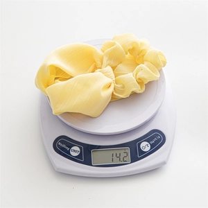 Close-up of a yellow daisy print chiffon scrunchie showing a lightweight weight of 14.2g