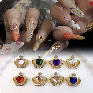 Macro view of gold crown nail charms featuring colorful heart gems and rhinestones