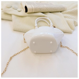 Close-up of white mini shell jelly bag with woven texture and gold chain strap