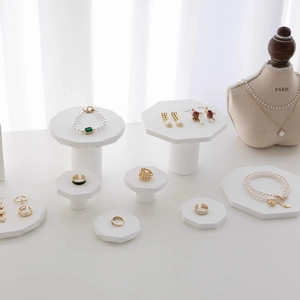 Minimalist white geometric jewelry display stands with gold rings and pearl necklaces