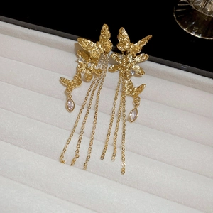 Detailed close-up of golden butterfly fringe earrings with crystal charms on jewelry tray