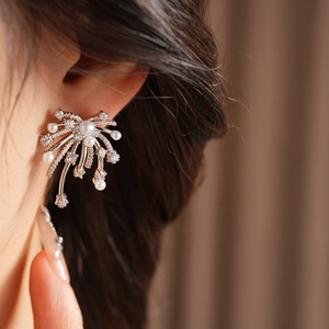 Close-up of a sparkling starburst pearl earring worn by a model in a luxury setting