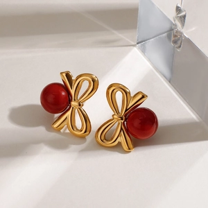 Boucles d'oreilles nœud dorées rétro avec perles rouge foncé sur marbre blanc, parure élégante