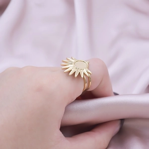 Detail of a golden sun-shaped ring with dual bands on elegant pink satin fabric