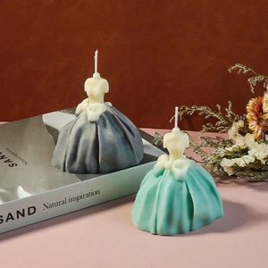 Artistic detail of dress-shaped candles with pleated skirts and bow decorations