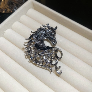 Macro shot of horse brooch with vine cutouts and sparkling crystal accents