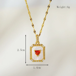 Detailed macro of gold heart pendant necklace with red gemstone and shell inlay 2.5cm