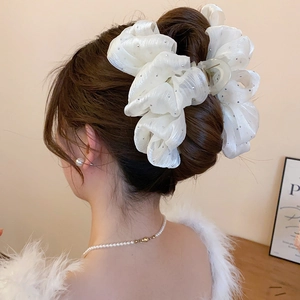 Macro shot of large white tulle hair claw clip with delicate rhinestone embellishments