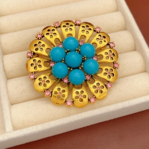 Detailed macro view of vintage golden flower brooch with blue beads and pink rhinestones