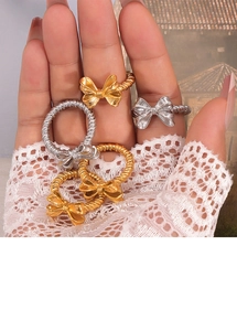 Dettaglio di anelli con fiocco in oro e argento e fascia a treccia su guanto di pizzo bianco