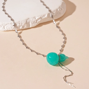 Vue macro du pendentif gourde en résine verte avec chaîne cœur et détail de gland