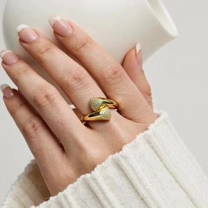 Detail of 18K gold-plated double heart open ring with zircons on model holding a cup