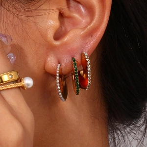 Gold earrings set with pearls and zircons shown as a close-up on a female model