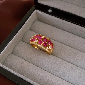 Macro view of gold plated ring with teardrop red stones and white zircon inlay
