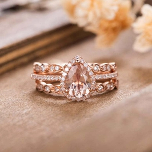 Three-piece rose gold ring set with pear cut champagne gemstone on wood surface