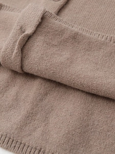 Close-up of fine knit texture and ribbed cuff detail on light camel wool cardigan