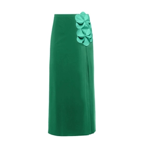 Detail of emerald green high-waist skirt featuring 3D floral accents and side slit design
