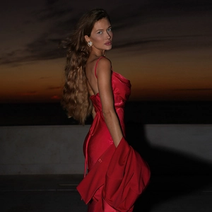 Detail of red satin dress texture with thin straps and elegant pearl earring styling