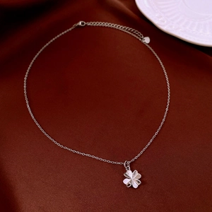 Macro shot of silver four-leaf clover pendant necklace on dark velvet texture