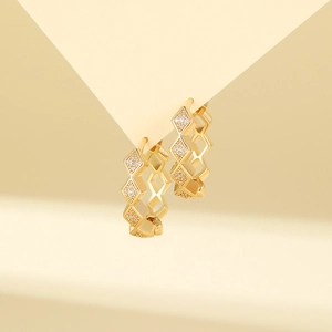 Macro detail of gold geometric earrings featuring cubic zirconia pavé and diamond shapes
