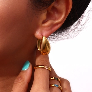 Detailed view of 18K gold teardrop earrings and colorful gemstone rings set