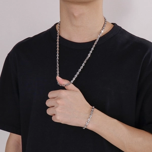 Detail of silver stainless steel pig nose chain set worn by male model on black tee