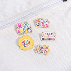 Detail of colorful enamel badges with motivational quotes pinned on a white canvas bag