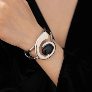 Detail view of retro silver oval black gemstone bracelet with spiral design and leather cords