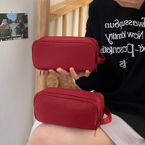 Detail view of the deep red nylon pencil case showing double zipper and sturdy side handle