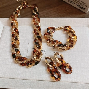 Detail view of gold and tortoiseshell link necklace, bracelet, and earrings set on tray