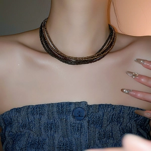 Close-up of multilayered brown and bronze bead choker necklace worn with denim outfit