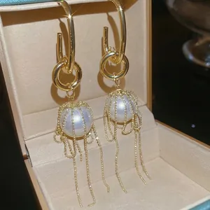 Elegant gold pearl tassel drop earrings with delicate bead chains in a jewelry box