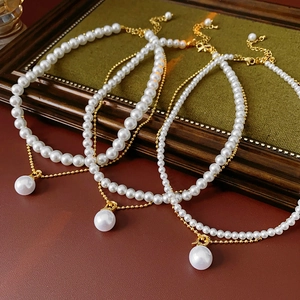 Detail of layered gold-plated necklaces with pearls on vintage frame and red background