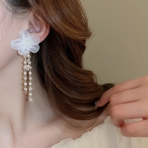 Detailed view of elegant white lace flower earrings with pearl tassels on model