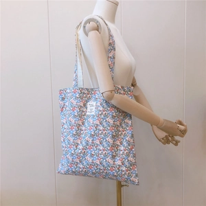Detail of floral canvas shoulder bag on mannequin showing pattern and strap design