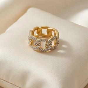 Detail shot of golden chain link ring featuring luxury pavé diamond accents on silk padding