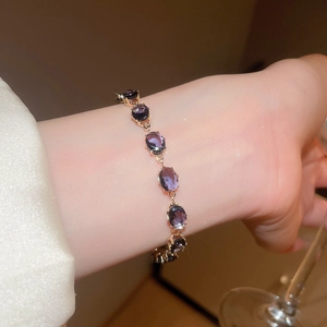 Close-up of elegant gold bracelet with oval purple gemstones on a woman's wrist