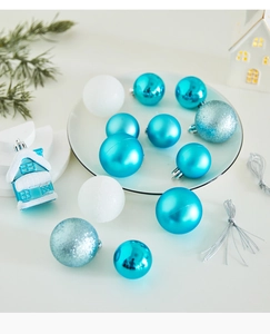 Close-up of blue and white Christmas ornaments with matte and glitter finishes in a snowy scene