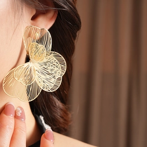Gros plan de boucles d'oreilles fleurs dorées évidées sur mannequin aux pétales en métal