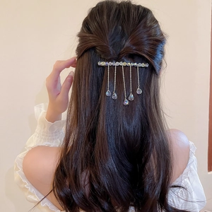 Detail of silver crystal hair clip with dangling tassels on a long spring barrette