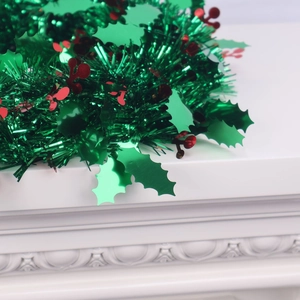 Detail of green and red Christmas garland with berries on a white fireplace mantle