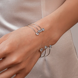 Détail du bracelet ouvert argenté multicouche avec zircons bleus sur tissu en soie champagne
