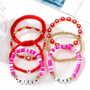 Detailed close-up of handmade red and pink clay bead bracelets with LOVE and KISS charms