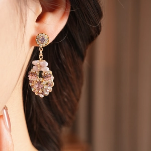 Close-up of pink crystal drop earrings with gold finish and rhinestone details on ear