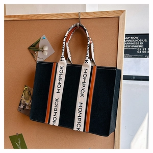 Detail of black felt tote bag featuring MOMPICK logo strap and sturdy fabric texture