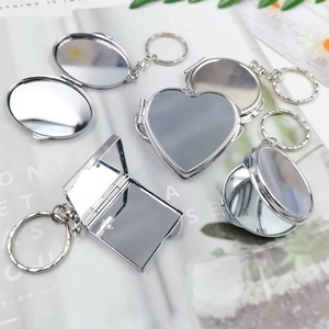 Divers porte-clés miroir de maquillage pliables en métal argenté sur une page de magazine