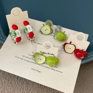 Detailed view of red and green enamel apple stud earrings on a fashion display card