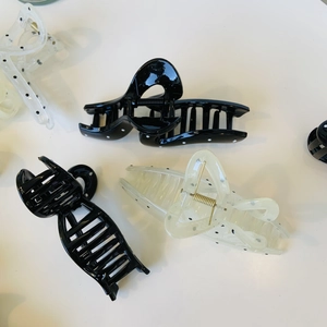 Detailed view of black and transparent polka dot claw clips for elegant hair styling