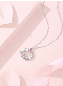 Macro shot of silver butterfly necklace featuring a pink heart gem and zircon stones